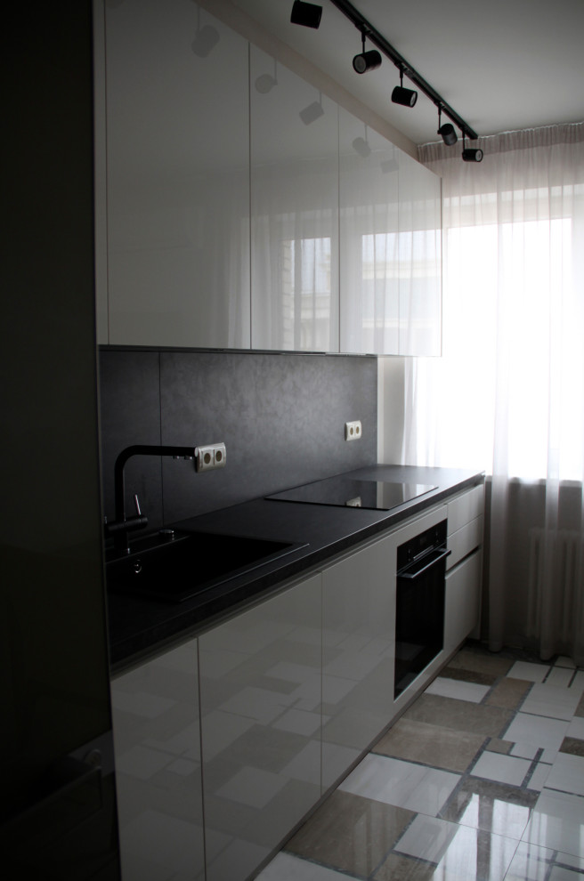 Immagine di una cucina contemporanea con lavello da incasso, ante lisce, paraspruzzi nero e top nero