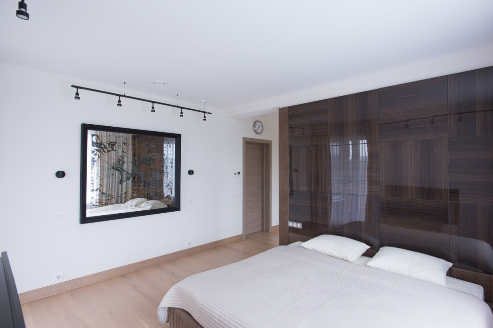 Свежая идея для дизайна: хозяйская спальня среднего размера в современном стиле с белыми стенами, деревянным полом, бежевым полом и панелями на части стены - отличное фото интерьера