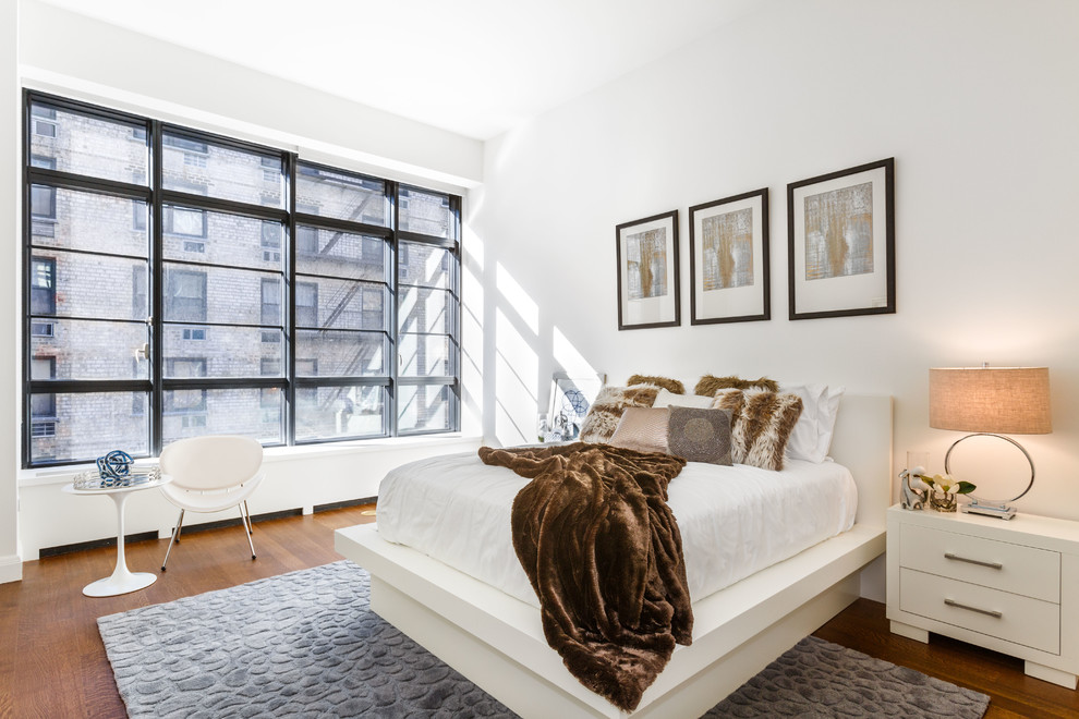 Photo of a contemporary bedroom in New York with white walls and medium hardwood floors.