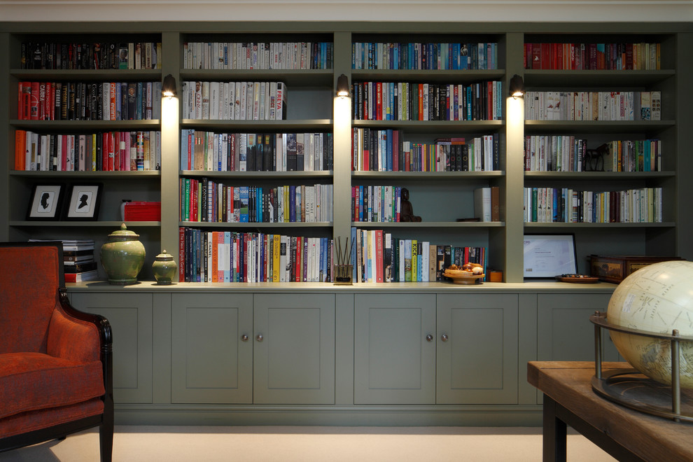 Photo of a large transitional home office in London with a library, green walls, carpet and beige floor.