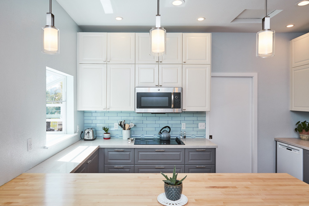 Mid-sized transitional u-shaped bamboo floor and brown floor eat-in kitchen photo with raised-panel cabinets, gray cabinets, blue backsplash, subway tile backsplash, a peninsula, an undermount sink, wood countertops, stainless steel appliances and white countertops
