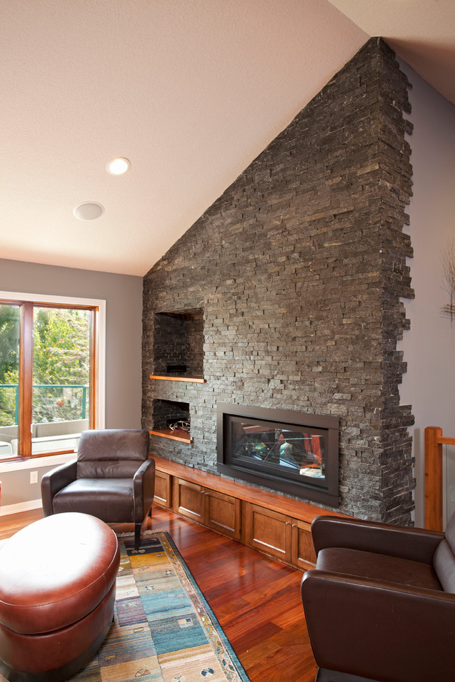 Inspiration for a mid-sized midcentury open concept family room in Minneapolis with medium hardwood floors, a standard fireplace, a stone fireplace surround and a built-in media wall.