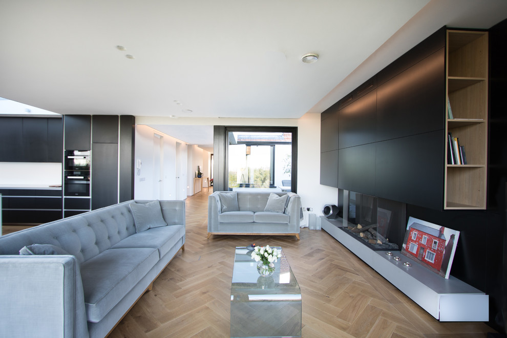 Scandinavian open concept living room in Dublin with black walls, light hardwood floors and a ribbon fireplace.