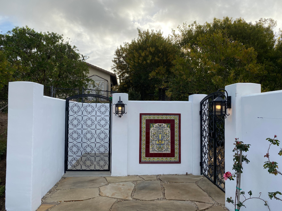 This is an example of an expansive mediterranean backyard full sun formal garden for summer in San Diego with with a gate and natural stone pavers.