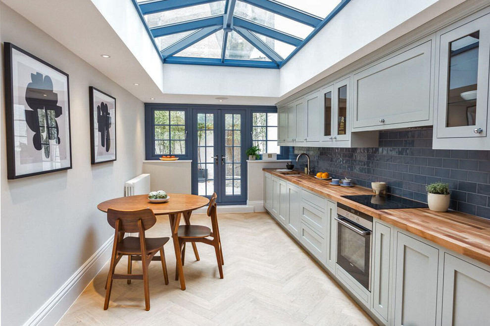 Inspiration for a transitional eat-in kitchen in London with an undermount sink, shaker cabinets, grey cabinets, wood benchtops, blue splashback, subway tile splashback and no island.