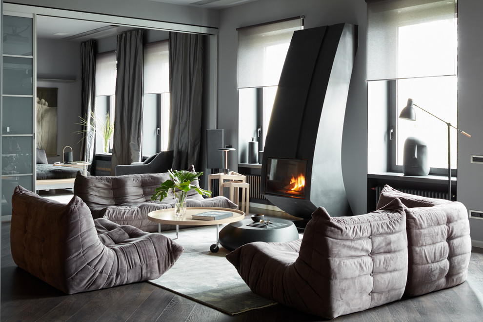 This is an example of a contemporary living room in Moscow with grey walls, dark hardwood floors, a standard fireplace and black floor.