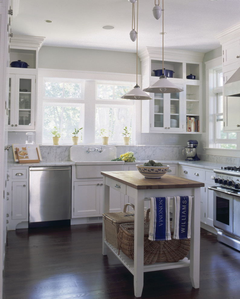 This is an example of a traditional kitchen in New York with glass-front cabinets, stainless steel appliances and a farmhouse sink.