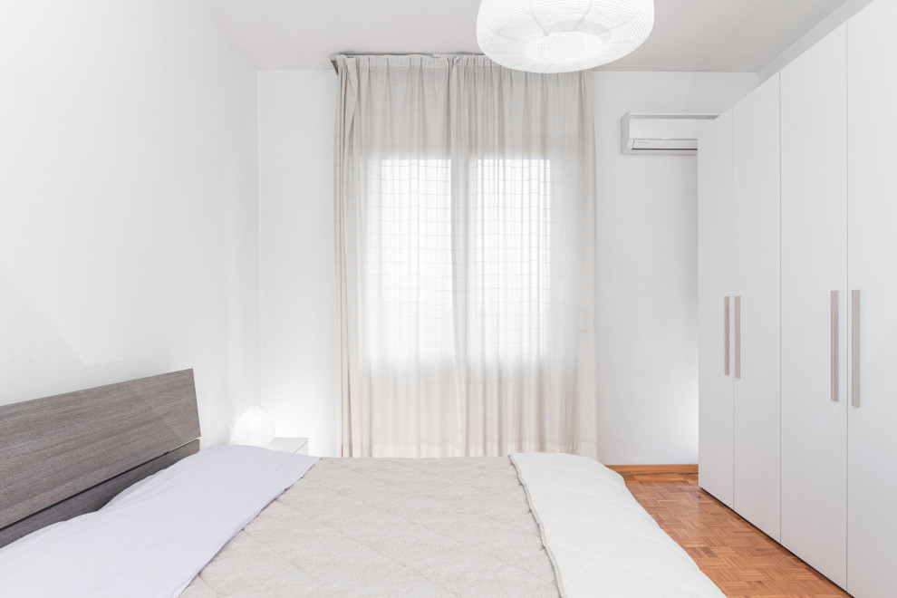 Modelo de dormitorio principal contemporáneo pequeño con paredes blancas, suelo de madera oscura y suelo marrón