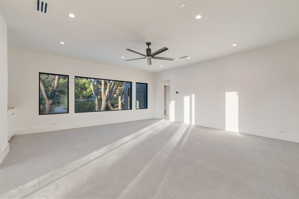 На фото: открытая гостиная комната в стиле ретро с белыми стенами, ковровым покрытием, телевизором на стене и серым полом с