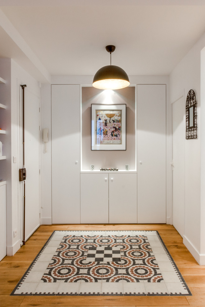 This is an example of a large contemporary vestibule in Paris with white walls and medium hardwood floors.