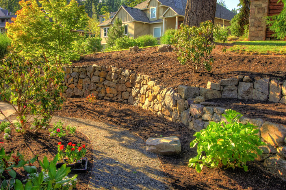 Inspiration for a large traditional sloped garden in Portland with a retaining wall.