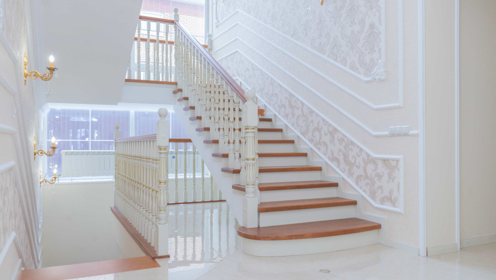 Aménagement d'un grand escalier classique en U avec des marches en bois, des contremarches en bois, un garde-corps en bois et du papier peint.