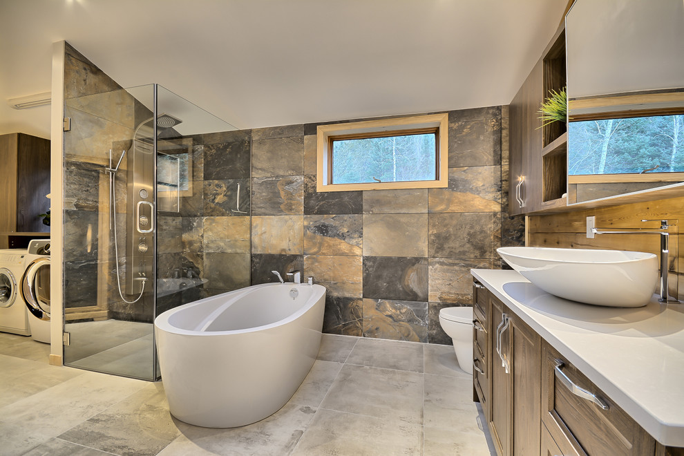 Mid-sized country master bathroom in Montreal with medium wood cabinets, a freestanding tub, a one-piece toilet, gray tile, beige tile, brown tile, ceramic tile, ceramic floors, a vessel sink, laminate benchtops, multi-coloured walls, recessed-panel cabinets and a curbless shower.