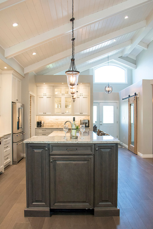 Eat-in kitchen - large transitional l-shaped eat-in kitchen idea with a double-bowl sink, shaker cabinets, white cabinets, beige backsplash, stainless steel appliances and an island