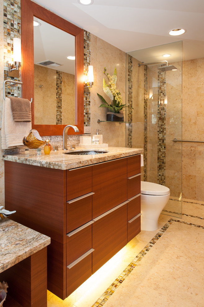 This is an example of a tropical bathroom in Hawaii with flat-panel cabinets, medium wood cabinets, an open shower, a two-piece toilet, white tile, stone tile, yellow walls, limestone floors, an undermount sink and granite benchtops.