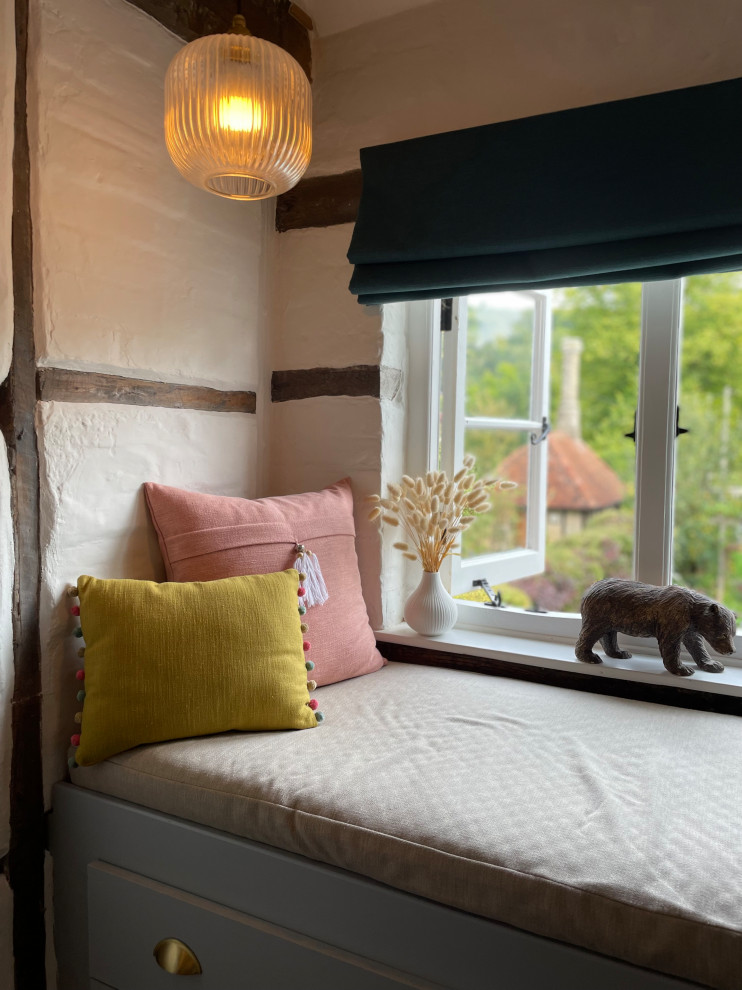 Kleines Modernes Hauptschlafzimmer mit beiger Wandfarbe, dunklem Holzboden, Kamin, Kaminumrandung aus Backstein, braunem Boden, freigelegten Dachbalken und Ziegelwänden in Hertfordshire