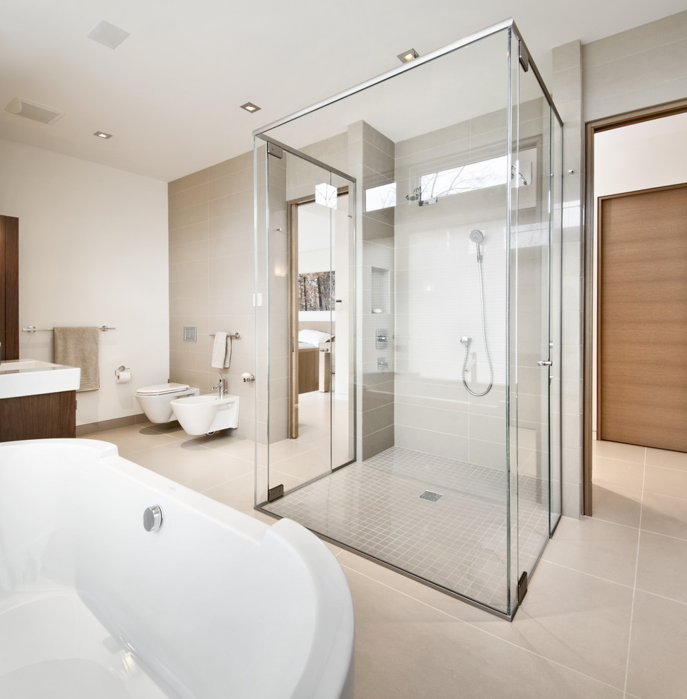 This is an example of a contemporary bathroom in Ottawa with flat-panel cabinets, dark wood cabinets, a freestanding tub, a curbless shower, a wall-mount toilet, beige tile and white walls.