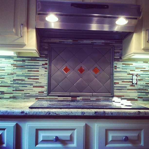 Example of a mid-sized transitional l-shaped enclosed kitchen design with a double-bowl sink, raised-panel cabinets, white cabinets, granite countertops, multicolored backsplash, matchstick tile backsplash, stainless steel appliances and no island