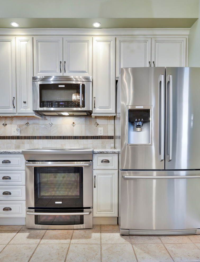 Example of a mid-sized transitional galley open concept kitchen design with a double-bowl sink, beaded inset cabinets, white cabinets, wood countertops, beige backsplash, ceramic backsplash, stainless steel appliances and a peninsula