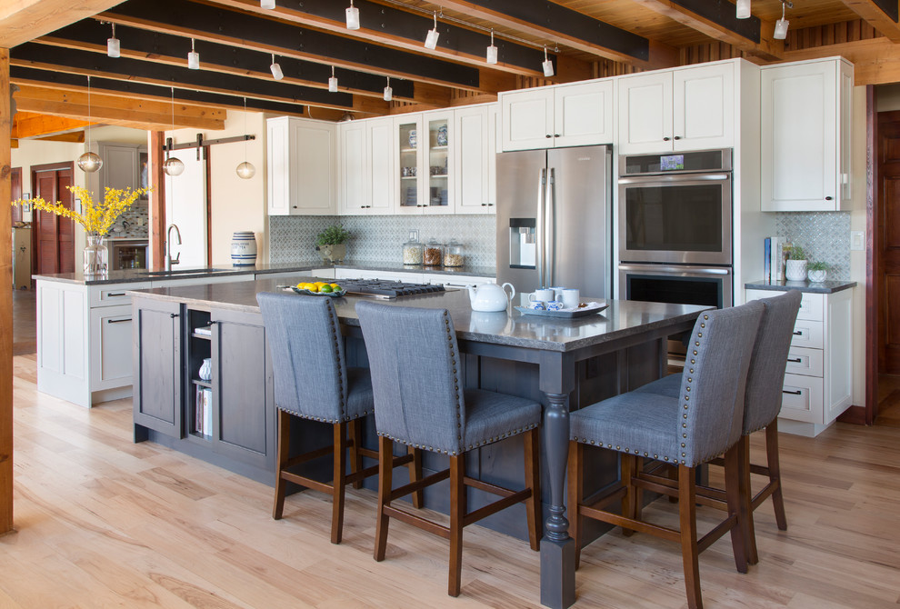 Example of a large transitional l-shaped light wood floor and beige floor open concept kitchen design in Denver with shaker cabinets, white cabinets, gray backsplash, stainless steel appliances, an island, gray countertops, an undermount sink and quartzite countertops