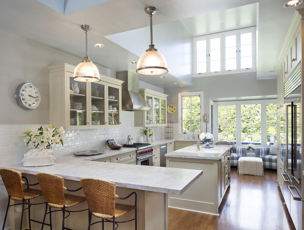 Example of a large classic u-shaped medium tone wood floor enclosed kitchen design in Los Angeles with an undermount sink, shaker cabinets, white cabinets, marble countertops, white backsplash, subway tile backsplash, stainless steel appliances and an island
