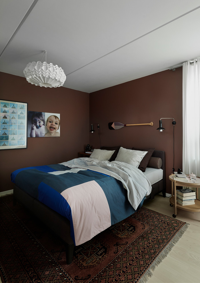 Contemporary bedroom in Copenhagen with brown walls, light hardwood floors and beige floor.
