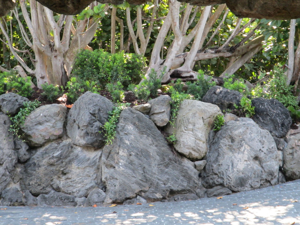 Inspiration for a mid-sized asian front yard driveway in Miami with a retaining wall and natural stone pavers.
