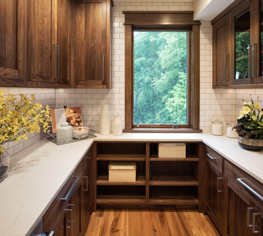 Inspiration for a mid-sized modern u-shaped kitchen pantry in Minneapolis with brown cabinets, quartz benchtops, white splashback, subway tile splashback, stainless steel appliances, medium hardwood floors, no island, brown floor and recessed-panel cabinets.