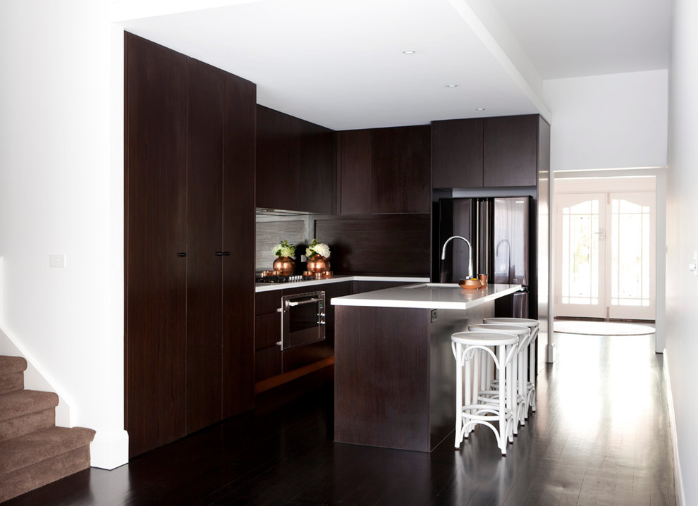 Design ideas for a large contemporary u-shaped kitchen pantry in Melbourne with an undermount sink, flat-panel cabinets, dark wood cabinets, soapstone benchtops, metallic splashback, mirror splashback, stainless steel appliances, dark hardwood floors and with island.