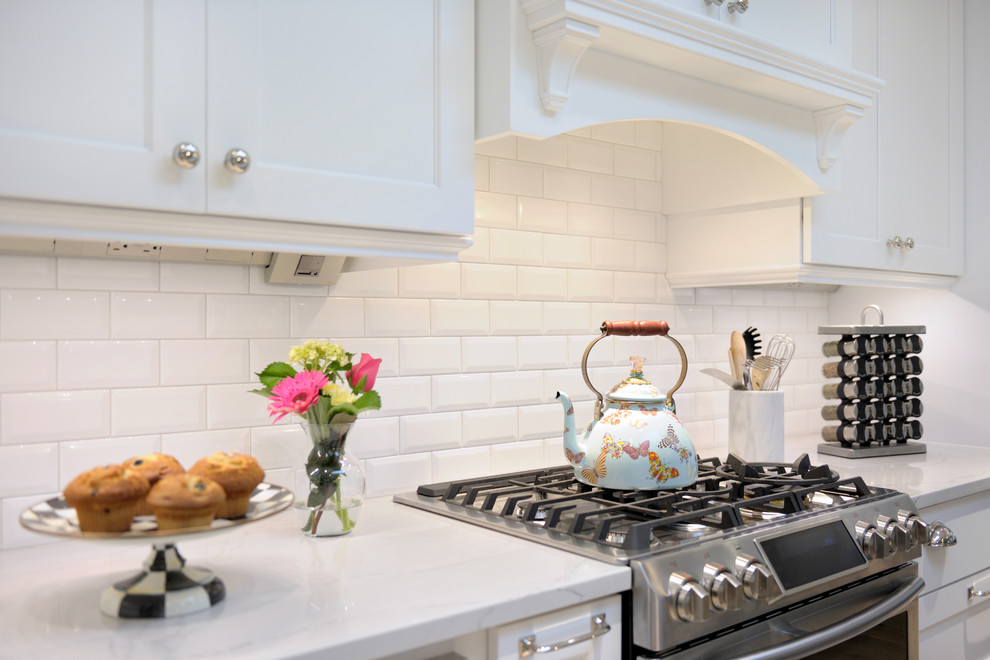 Example of a large transitional l-shaped eat-in kitchen design in St Louis with a farmhouse sink, shaker cabinets, white cabinets, quartz countertops, white backsplash, stainless steel appliances, an island and porcelain backsplash