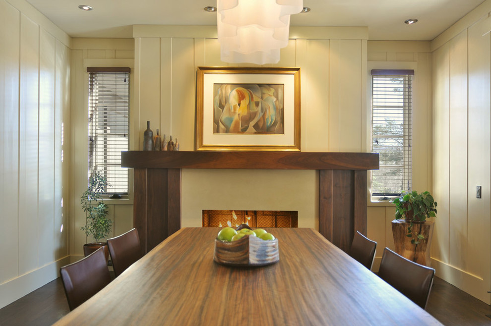 This is an example of a mid-sized transitional separate dining room in Other with beige walls, dark hardwood floors, a standard fireplace, a wood fireplace surround and brown floor.