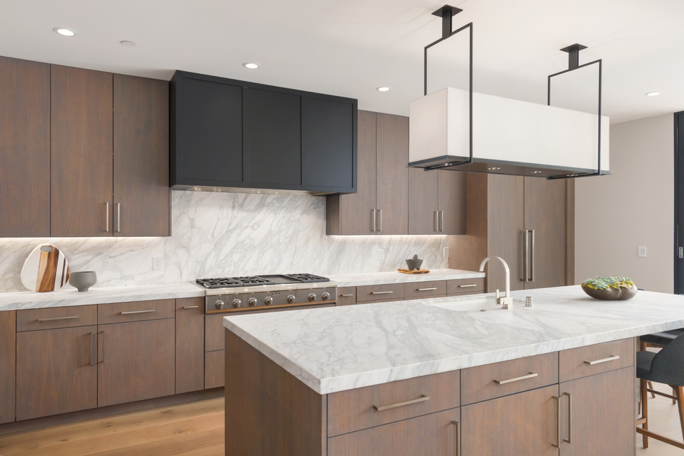 Photo of a large contemporary l-shaped open plan kitchen in San Francisco with an undermount sink, flat-panel cabinets, brown cabinets, marble benchtops, white splashback, stone slab splashback, panelled appliances, light hardwood floors, with island, brown floor and white benchtop.