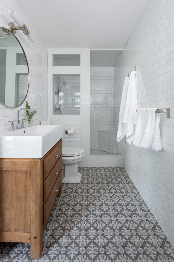 Inspiration for a large transitional 3/4 bathroom in Boston with flat-panel cabinets, brown cabinets, an alcove shower, a one-piece toilet, white tile, subway tile, white walls, ceramic floors, an integrated sink, solid surface benchtops, grey floor and an open shower.