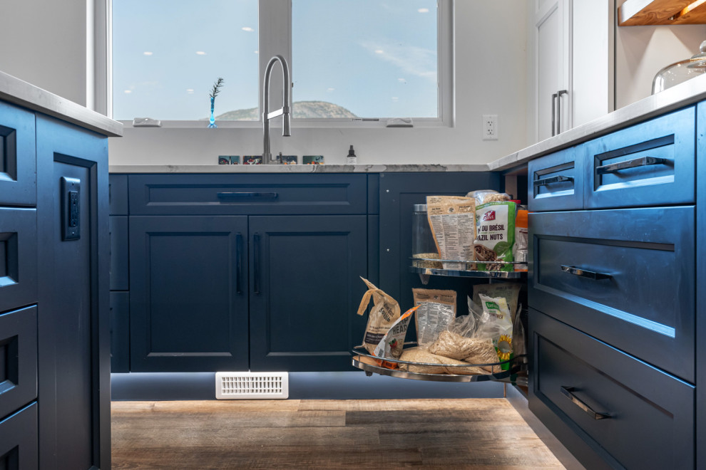 Large transitional u-shaped dark wood floor and brown floor eat-in kitchen photo with an undermount sink, recessed-panel cabinets, blue cabinets, quartz countertops, white backsplash, ceramic backsplash, stainless steel appliances, an island and white countertops