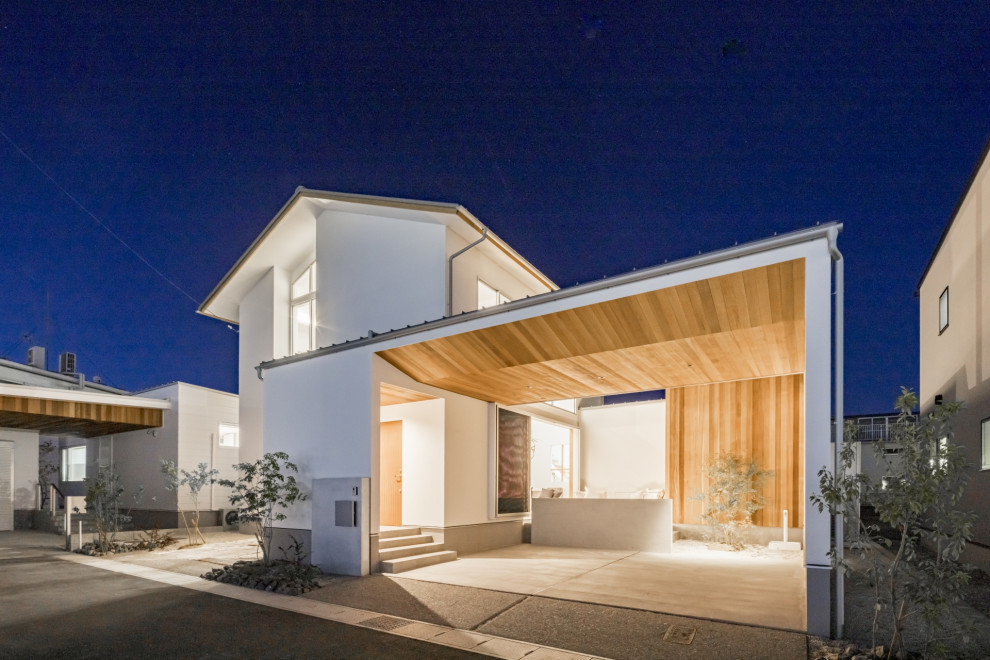 Cette image montre une façade de maison blanche minimaliste en stuc à un étage avec un toit à deux pans et un toit en métal.