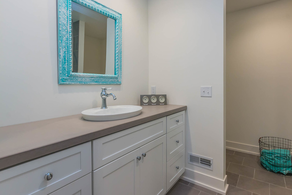 This is an example of a mid-sized beach style 3/4 bathroom in Grand Rapids with shaker cabinets, white cabinets, white walls, porcelain floors, a drop-in sink and engineered quartz benchtops.