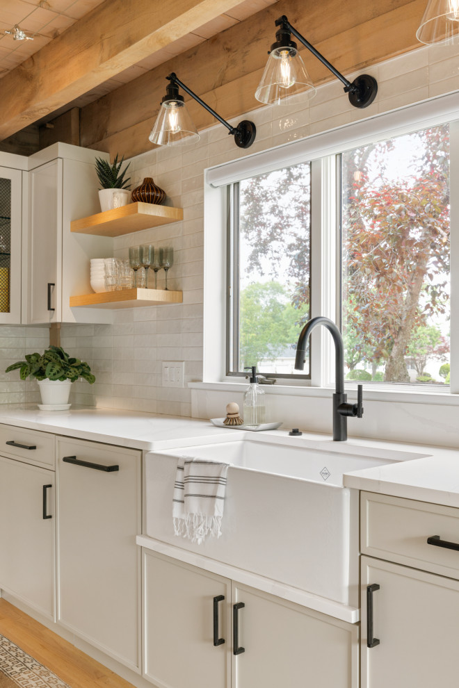 Kitchen - transitional l-shaped light wood floor and exposed beam kitchen idea in Boston with a farmhouse sink, shaker cabinets, gray cabinets, quartz countertops, white backsplash, ceramic backsplash, paneled appliances, an island and white countertops