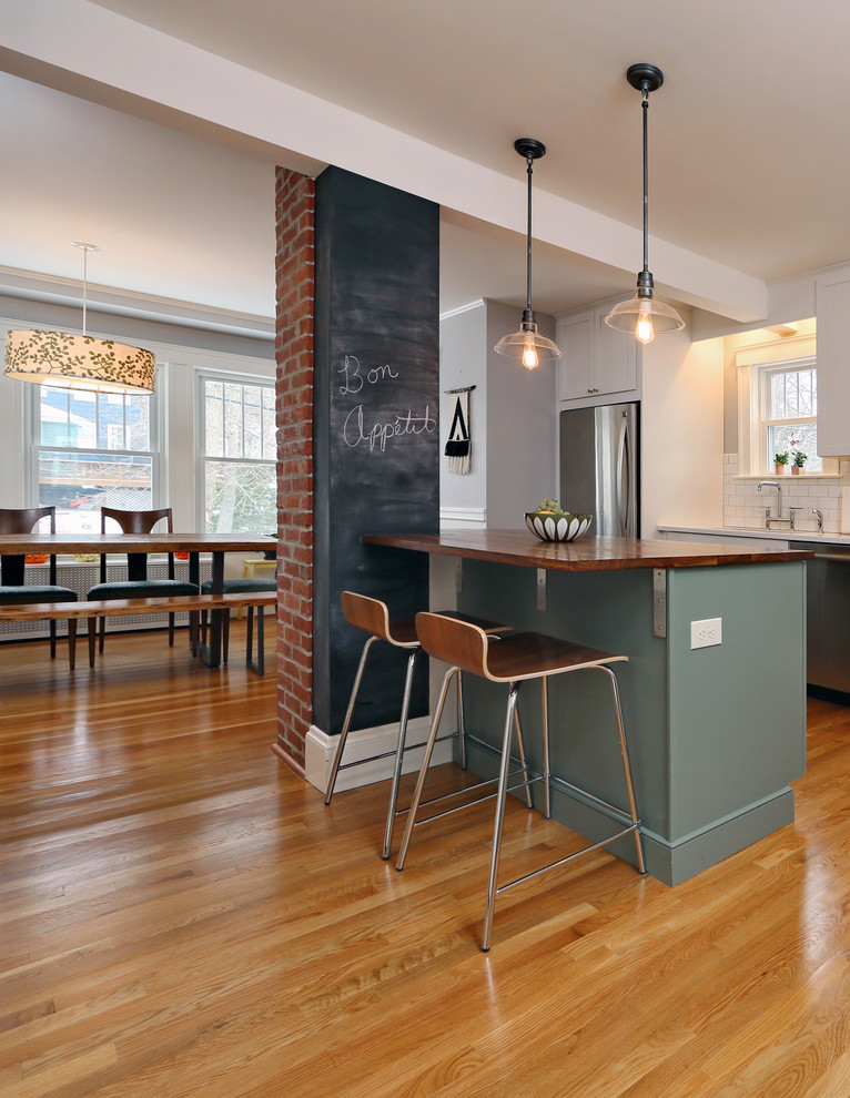 Kitchen - small contemporary u-shaped medium tone wood floor kitchen idea in Boston with an undermount sink, shaker cabinets, green cabinets, wood countertops, white backsplash, subway tile backsplash, stainless steel appliances and an island
