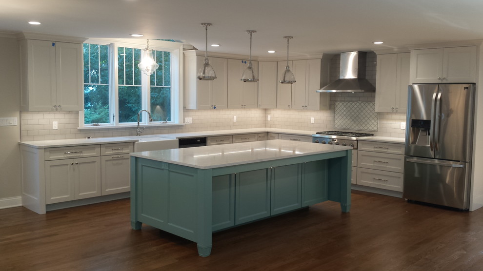 Photo of a large arts and crafts u-shaped eat-in kitchen in Chicago with a farmhouse sink, white cabinets, quartzite benchtops, white splashback, ceramic splashback, stainless steel appliances, dark hardwood floors, with island, brown floor, white benchtop and shaker cabinets.