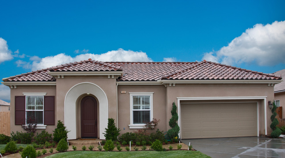Mid-sized mediterranean one-storey stucco beige house exterior in Other with a gable roof and a tile roof.