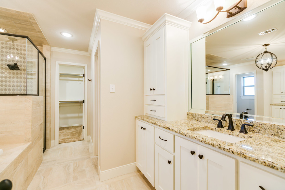 Inspiration for a large transitional master bathroom in Austin with shaker cabinets, white cabinets, a drop-in tub, an alcove shower, a one-piece toilet, beige tile, porcelain tile, beige walls, porcelain floors, an undermount sink, granite benchtops, beige floor and a hinged shower door.