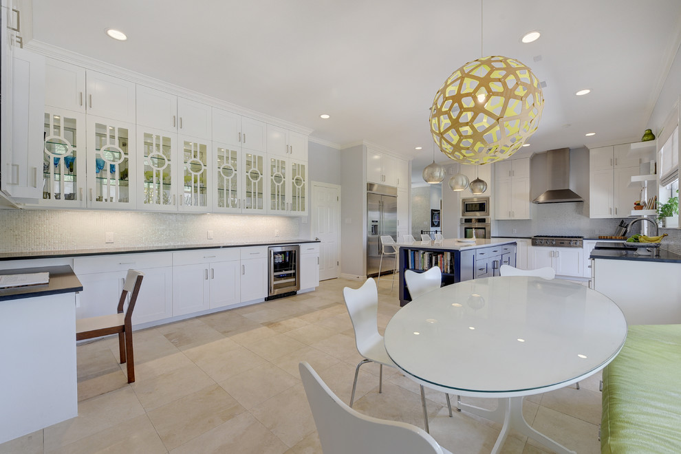 Enclosed kitchen - large transitional travertine floor enclosed kitchen idea in Austin with a farmhouse sink, shaker cabinets, white cabinets, solid surface countertops, metallic backsplash, mosaic tile backsplash, stainless steel appliances and an island