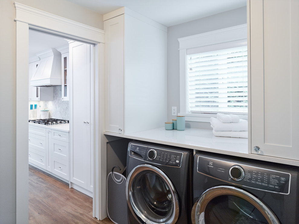 Design ideas for a beach style laundry room in Vancouver with shaker cabinets, white cabinets, granite benchtops, vinyl floors, a side-by-side washer and dryer, brown floor and white benchtop.