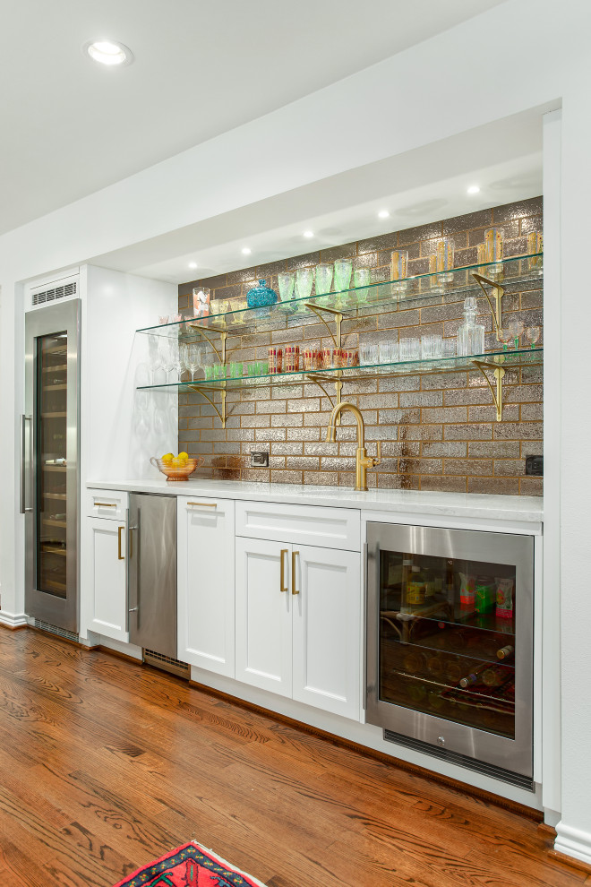 Large traditional l-shaped home bar in Dallas with an undermount sink, recessed-panel cabinets, white cabinets, quartz benchtops, white splashback, ceramic splashback, medium hardwood floors, brown floor and white benchtop.