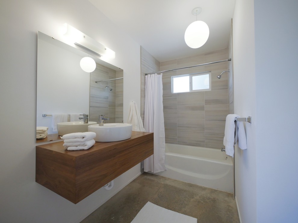 Photo of a small midcentury bathroom in Los Angeles with medium wood cabinets, white walls, concrete floors and a wall-mount sink.