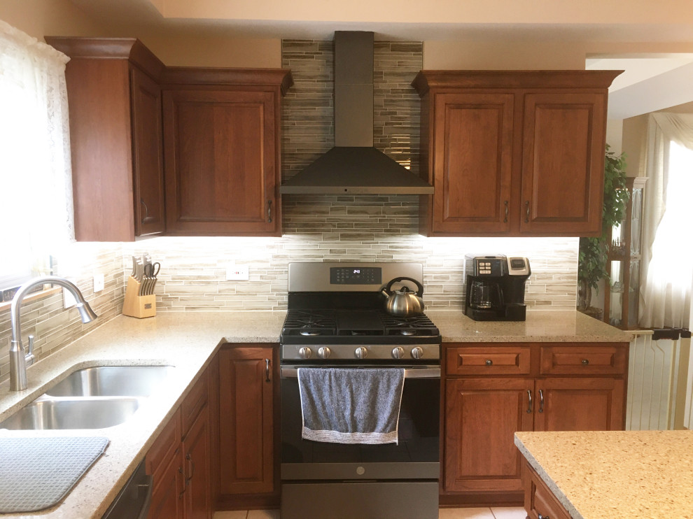 Cette image montre une cuisine américaine traditionnelle en L et bois brun de taille moyenne avec un placard avec porte à panneau surélevé, un plan de travail en quartz modifié et îlot.