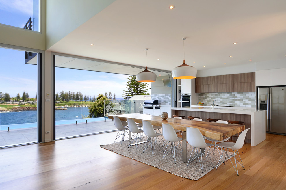 Mid-sized contemporary galley eat-in kitchen in Wollongong with a double-bowl sink, flat-panel cabinets, medium wood cabinets, quartz benchtops, grey splashback, terra-cotta splashback, stainless steel appliances, medium hardwood floors and with island.