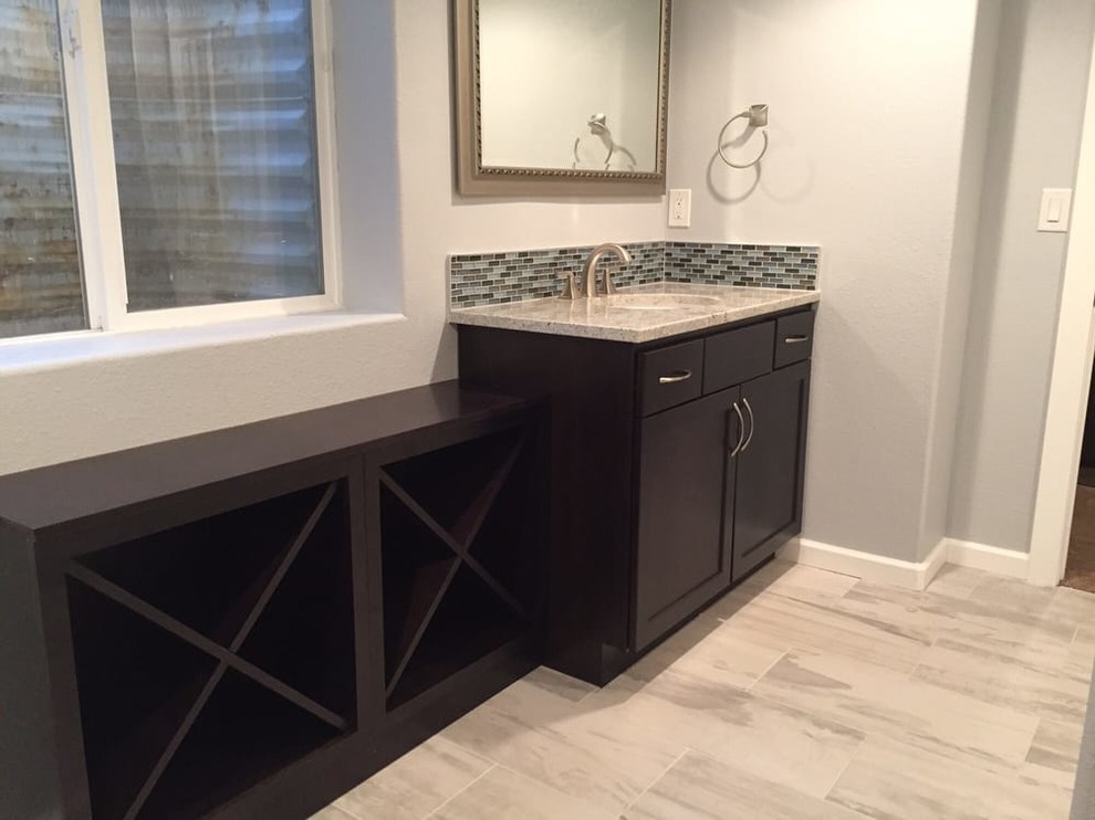 Photo of a mid-sized transitional 3/4 bathroom in Denver with shaker cabinets, dark wood cabinets, black tile, blue tile, gray tile, matchstick tile, grey walls, porcelain floors, granite benchtops, an alcove tub, a shower/bathtub combo, a one-piece toilet, an undermount sink and grey floor.