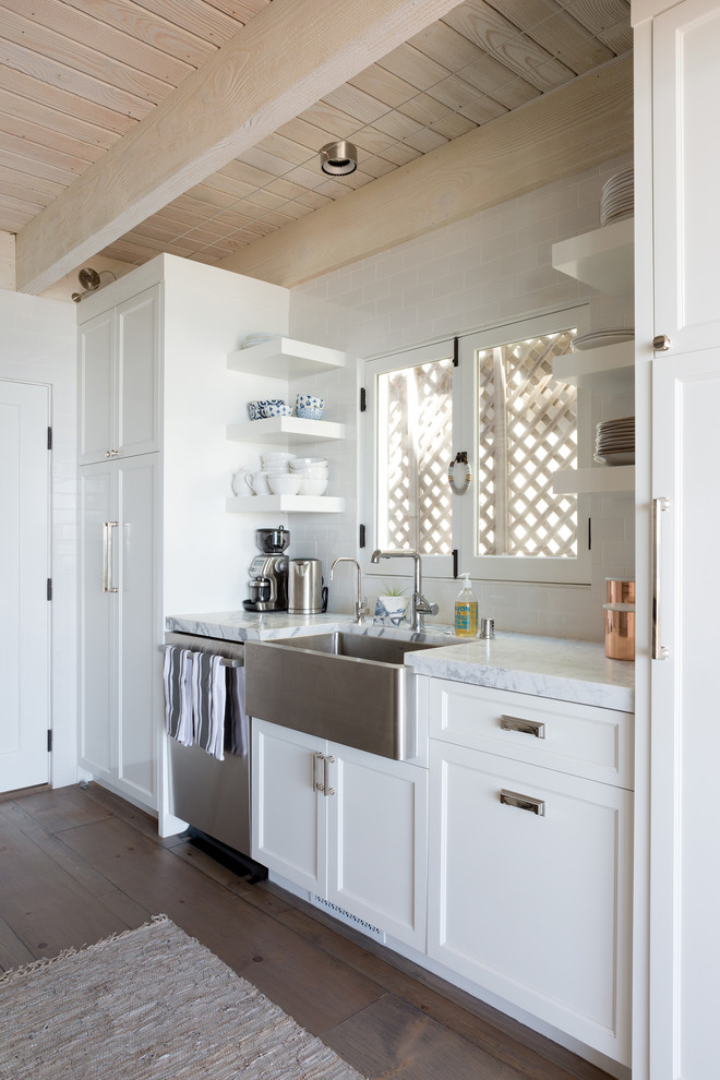 This is an example of a small beach style galley eat-in kitchen in Los Angeles with a farmhouse sink, shaker cabinets, white cabinets, marble benchtops, white splashback, ceramic splashback, stainless steel appliances, porcelain floors, no island and grey floor.