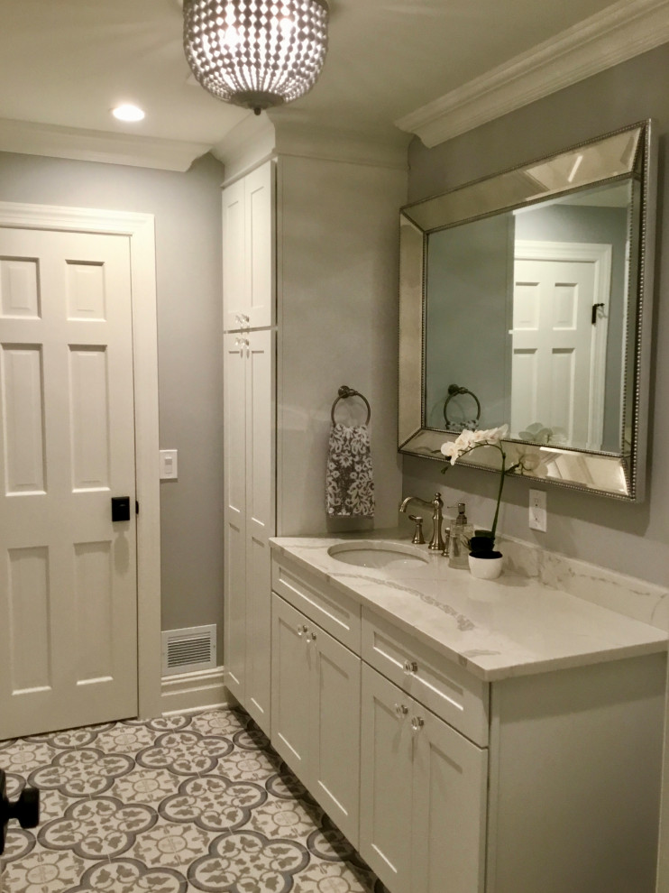 Inspiration for a mid-sized country powder room in New York with shaker cabinets, white cabinets, a one-piece toilet, grey walls, ceramic floors, an undermount sink, engineered quartz benchtops, grey floor, white benchtops and a freestanding vanity.